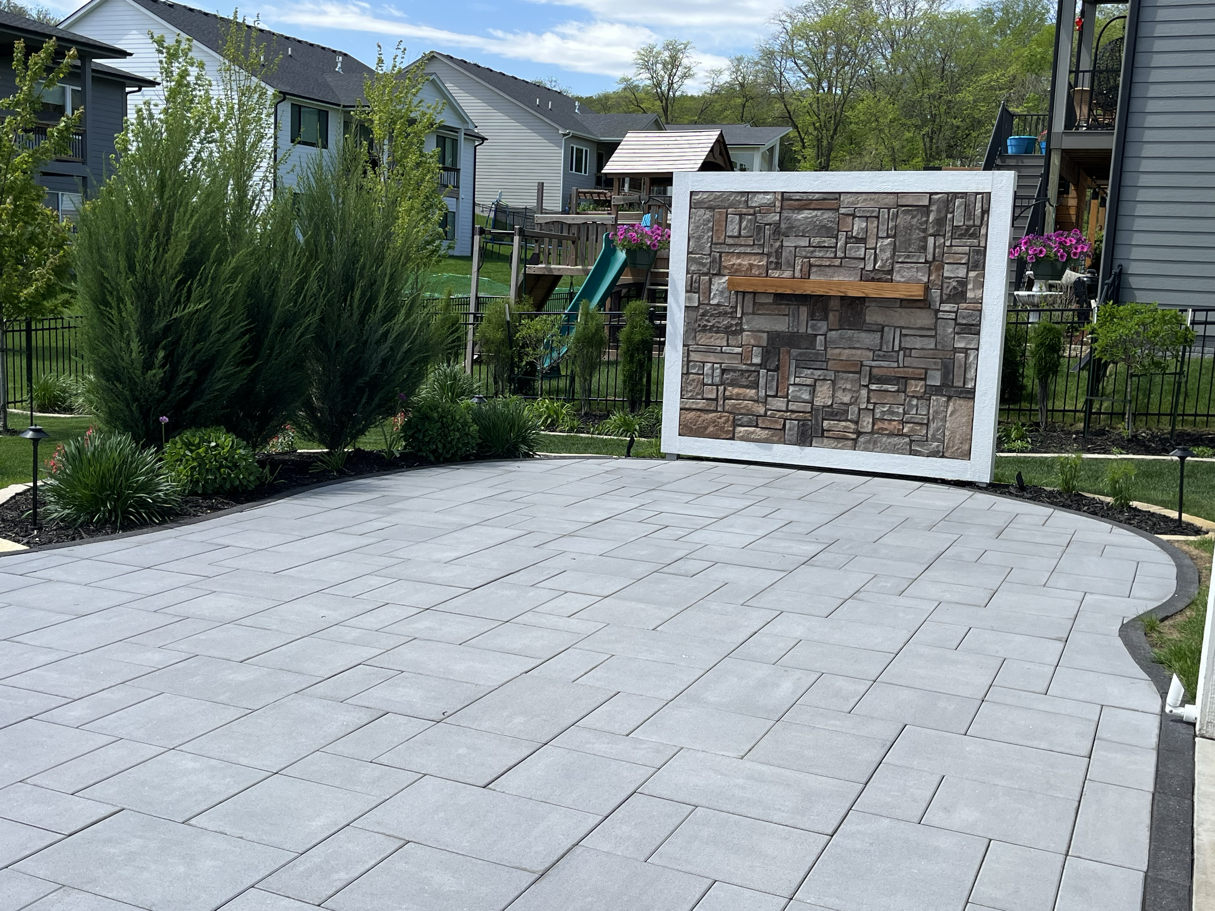 paver patio with a multicolored stone wall with mantle at the end. 